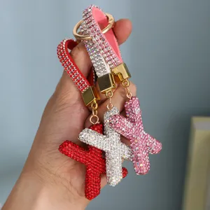 Detailed view of three luxury rhinestone-encrusted letter X keychains in varied colors