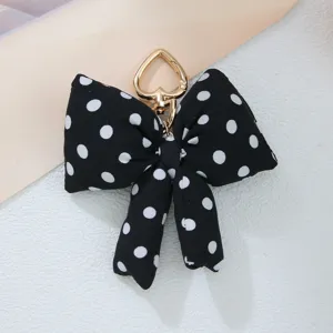 Detailed view of a black and white polka dot padded bow charm with a gold heart clip