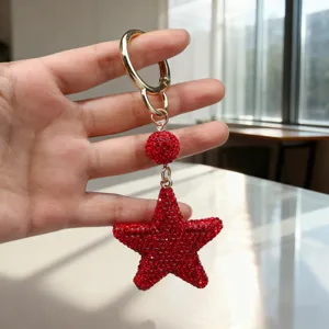 Detailed close-up of a sparkling red rhinestone star keychain held in hand for scale