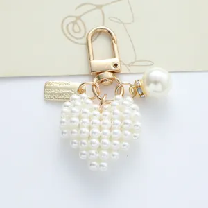 Macro view of the white pearl heart charm and gold tag on the heart keychain.