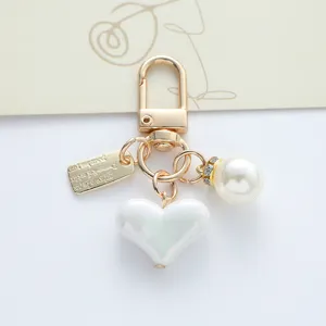 Detailed view of iridescent heart and pearl charms on a stylish golden alloy keychain