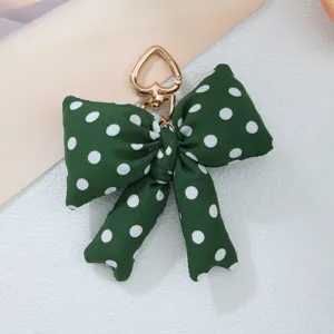 Close-up detail of a green polka dot fabric bow featuring a gold heart-shaped metal clasp