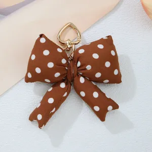 Detailed macro view of the brown polka dot fabric bow and heart-shaped gold clasp