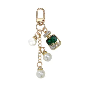 Llavero de perlas con dije de frasco de perfume verde y brillantes piedras de strass