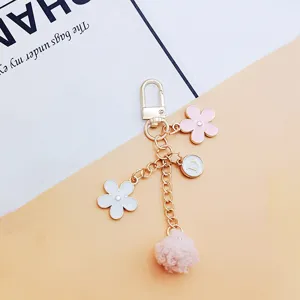 Close-up detail of Japanese style floral and pink fuzzy pom-pom keychain pendant charm