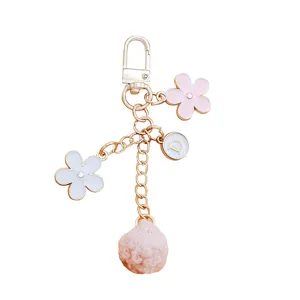 Cute floral keychain with personalized letter charm and soft pink pom-pom for bags
