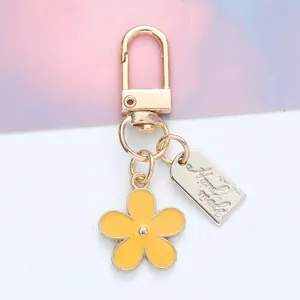 Detail shot of a yellow daisy flower keychain featuring a 'Hand made' metal tag