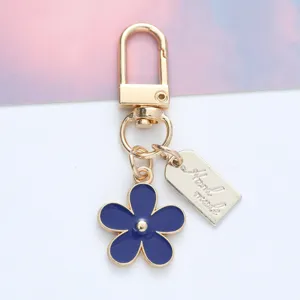 Detail of a blue enamel daisy keychain with a "Hand made" gold metal tag