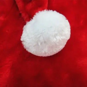Close-up detail of soft white plush pom-pom on red Christmas costume fabric