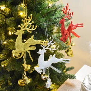Glittery Christmas reindeer ornaments with bells hanging on a warm lit Xmas tree