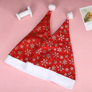 Dettaglio di due cappelli di Natale rossi con fiocchi di neve bianchi su sfondo rosa