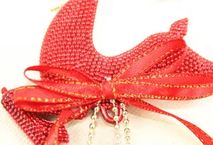 Close-up of a handmade red beaded Christmas ornament with a gold-edged ribbon bow