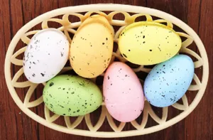 Close-up view of colorful speckled foam Easter eggs arranged in a beige lattice basket