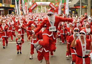 Crowd of people wearing red Santa Claus costumes during a festive marathon event outdoors