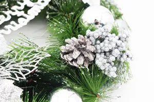 Macro detail of Christmas wreath with silver baubles, pine cone, and glittery berries