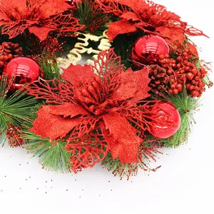 Detail close-up of red poinsettias and ornaments on a lush green Christmas wreath