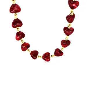 Close-up detail of dark red marbled resin heart beads and gold spacers on a necklace