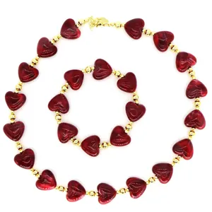 Detail of vintage jewelry set featuring marbled red resin hearts and polished golden beads