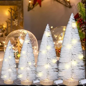 Cuatro mini árboles de Navidad blancos con luces LED cálidas sobre bases de madera