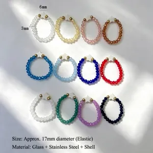 Set of 12 colorful glass beaded elastic rings with white shell star charms.