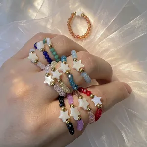 Detail of bohemian elastic rings featuring colorful beads and shell star charms