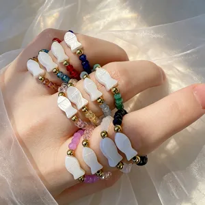 Detailed view of handmade beaded elastic rings with colorful glass and shell fish charms.