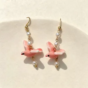 Exquisite handmade pink ceramic pigeon earrings featuring elegant pearls and gold hooks
