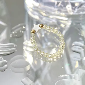 Detailed view of handmade beaded elastic ring with white star and faceted glaze beads