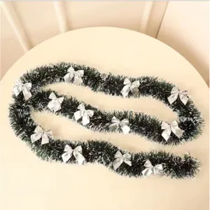 Dark green Christmas tinsel garland with white snow tips and decorative silver bows