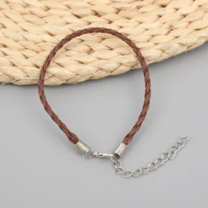 Detailansicht eines braunen geflochtenen Wachskordel-Armbands mit silberner Kette