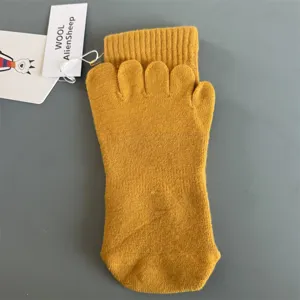 Detailansicht von gelben Woll-Zehensocken mit getrennten Zehenfächern und Markenanhänger.