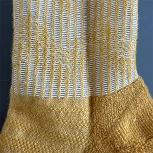 Detaillierte Nahaufnahme der gelb-weißen Wollmischung Halbfrottee Zehensocke Stricktextur.