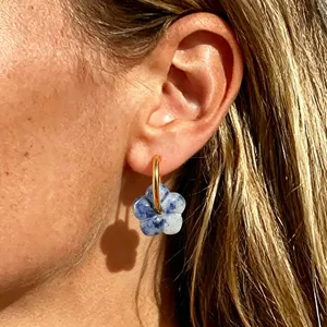 Nahaufnahme eines böhmischen Naturstein-Blumenohrrings mit goldenem Creolen aus Edelstahl