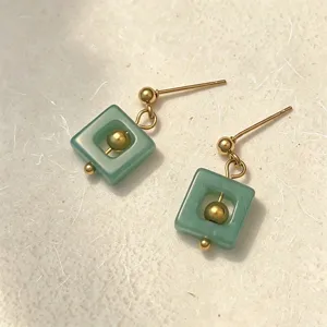 Nahaufnahme minimalistischer quadratischer Ohrringe aus grünem Naturstein mit Goldfinish