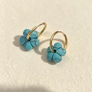 Nahaufnahme böhmischer Türkis-Blumenohrringe mit polierten, goldfarbenen Edelstahl-Creolen