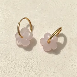 Detaillierte Ansicht von rosa Naturstein-Blumenohrringen mit goldenen Edelstahlreifen.