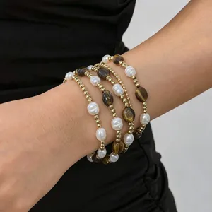 Close-up of layered stainless steel bracelet with freshwater pearls and tiger eye stones.