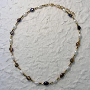 Close-up of elegant handmade necklace featuring natural pearls and tiger eye stone beads