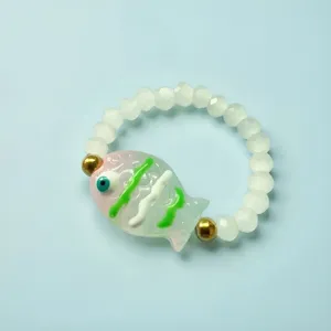 Primo piano di un ciondolo a forma di pesce in vetro su un anello elastico bianco