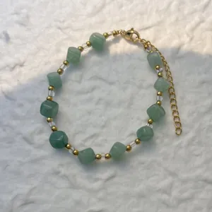 Detailed view of the green stone beads and gold-tone chain on the bracelet