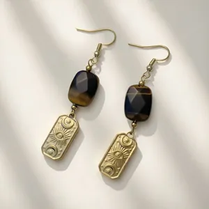 Macro detail of vintage gold earrings with moon eye motif and dark natural stone.
