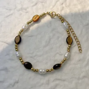 Detail view of a handmade bracelet with freshwater pearls and natural brown stones.