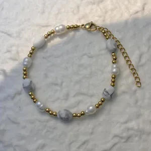 Macro view of a mixed bracelet featuring freshwater pearls and marble-patterned stones.