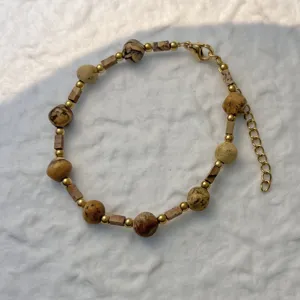 Detailed view of natural stone beads and gold stainless steel chain on a white background.
