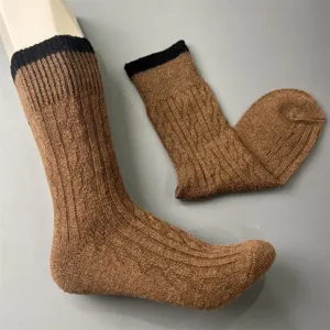 Detail view of brown merino wool knit mid-calf socks with cable pattern and black cuff.