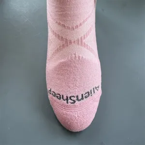 Close-up detail of pink knitted merino wool athletic crew sock texture and toe branding.