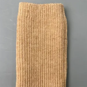 Close-up detail of soft merino wool ribbed knit sock fabric in neutral camel color texture.