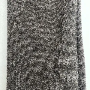 Close-up detail shot of merino wool blend fabric, soft knit texture, dark grey tone.