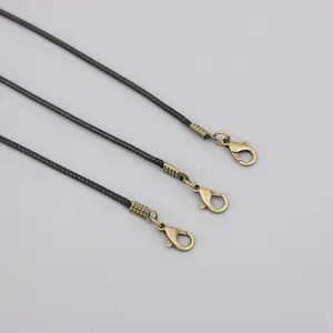 Detailed macro view of black waxed cord necklaces featuring antique bronze lobster clasps