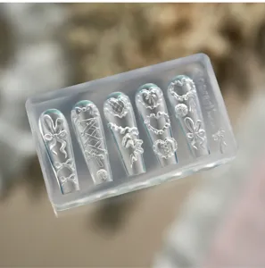 Detailansicht einer 3D-Silikon-Nagelkunstform mit eingravierten Schleifen- und Herzdesigns.